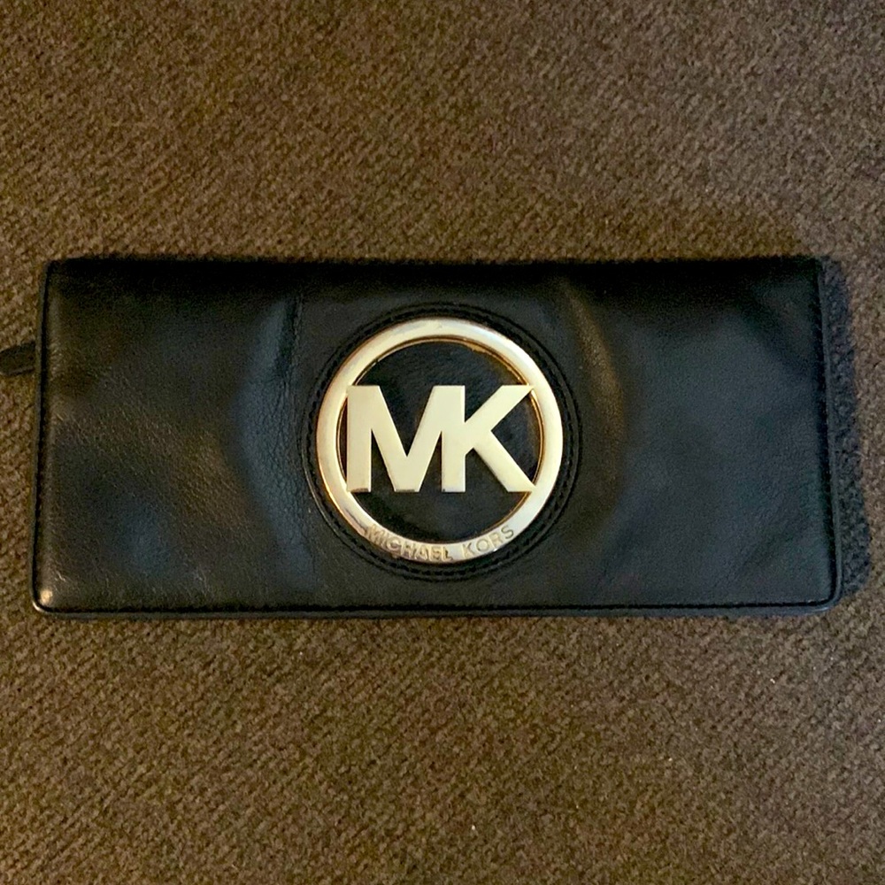 Black leather Michael Kors wristlet with gold tone logo.